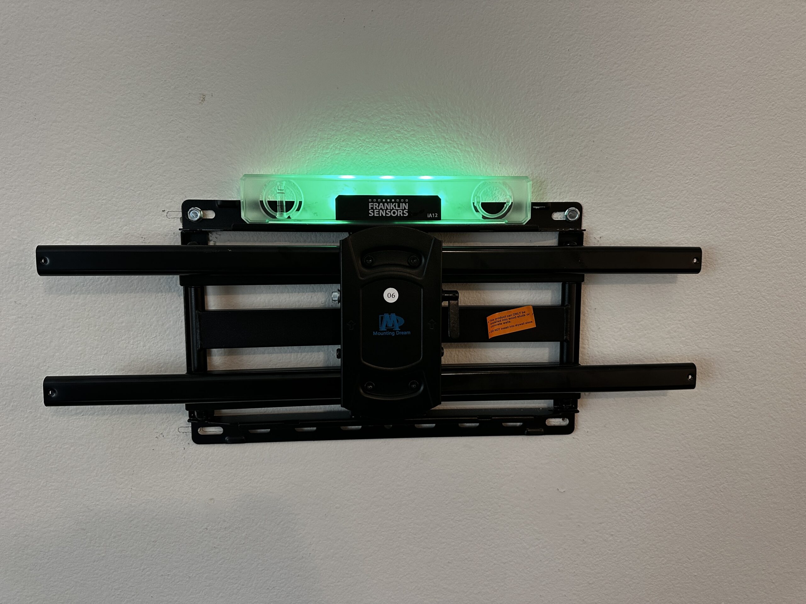Full-motion articulating TV wall mount being leveled with a laser level during installation