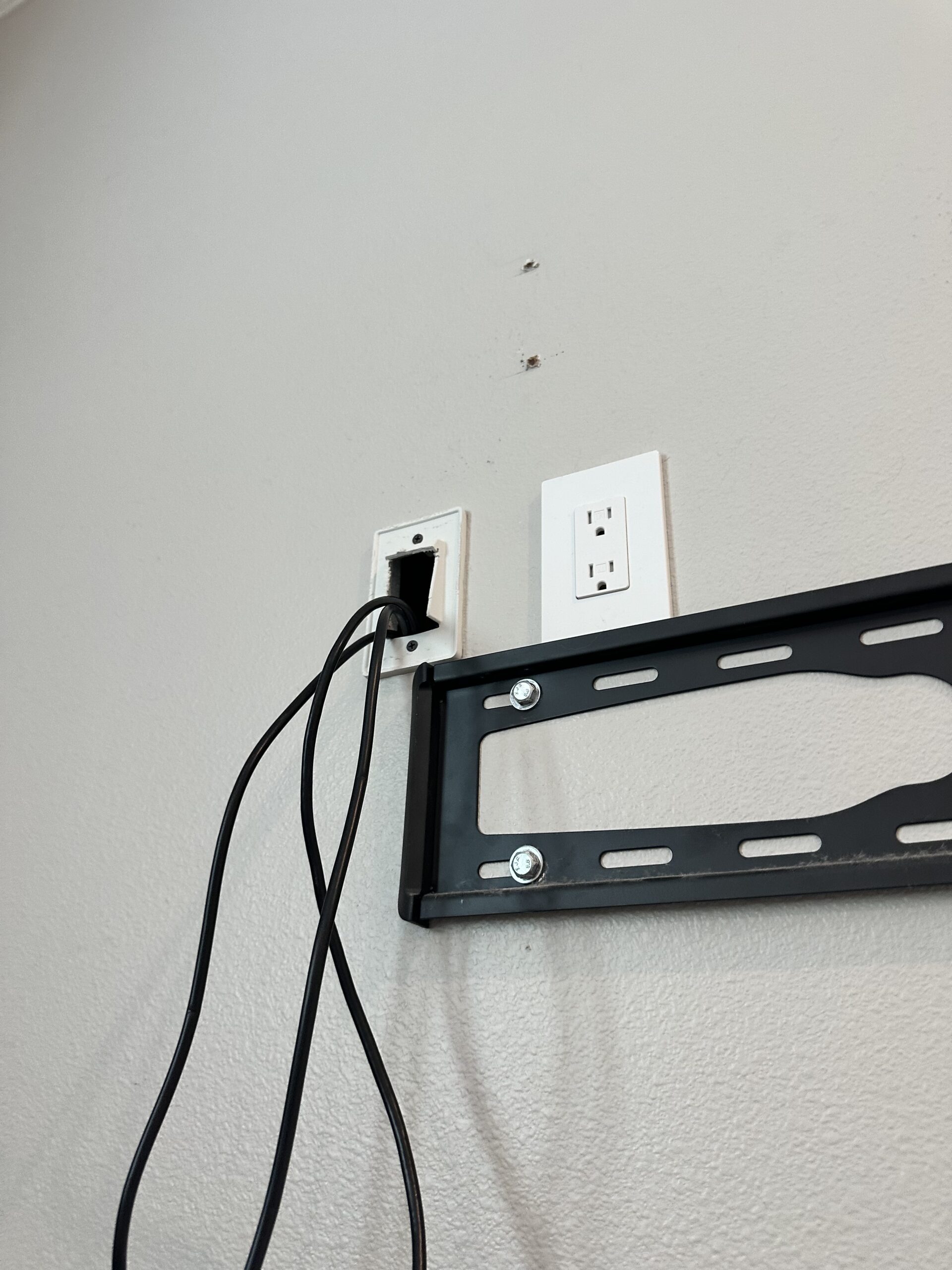 Tilting TV wall mount installed with a recessed in-wall power outlet and cable pass-through plate