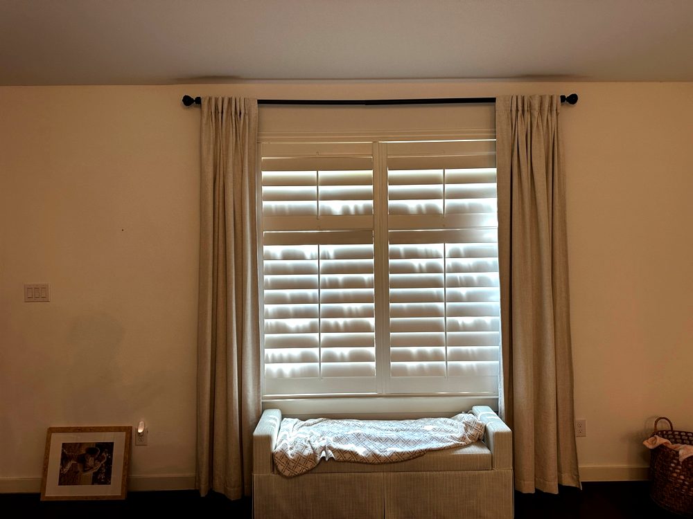 Curtain rod and drapes installed over plantation shutters in a Dallas bedroom