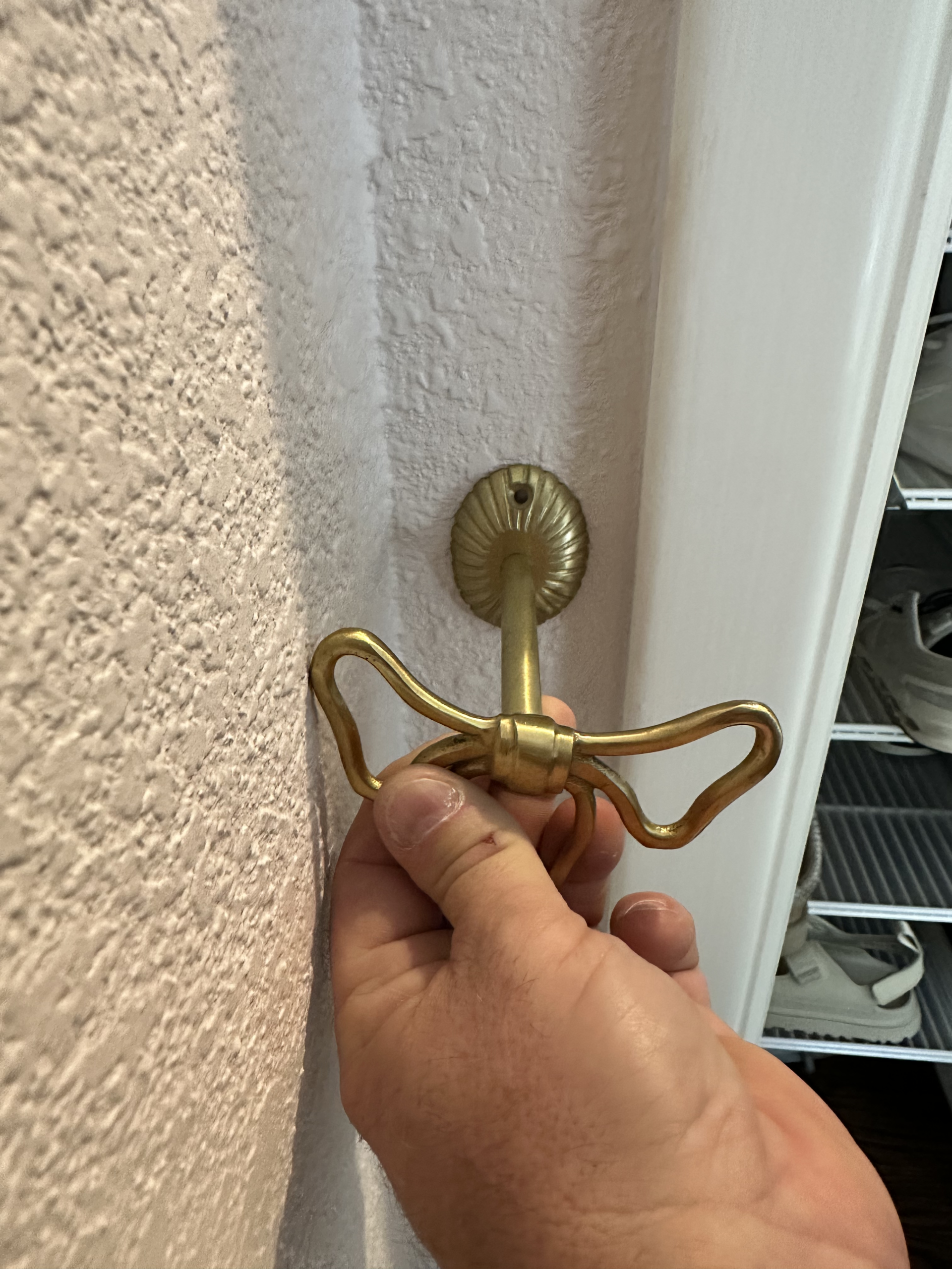 Brass bow-shaped curtain tieback being installed beside a closet door