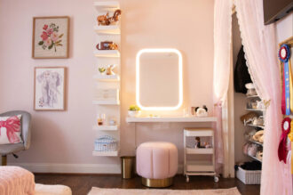 Finished girls' bedroom in Lakewood with a tall white wall shelf unit, a floating makeup desk with a lighted mirror, and a closet curtain held by a brass bow tieback